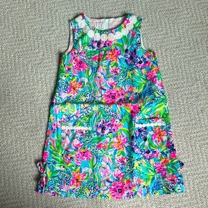 Classic sleeveless shift dress with hem bows and pockets.